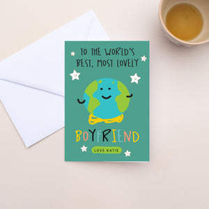 Greeting card for a boyfriend with a cartoon character and text on a teal background, next to an envelope and cup of tea.