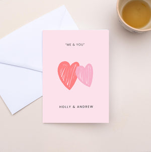 Greeting card with two hearts and text 'Me & You' on a light surface with an envelope.