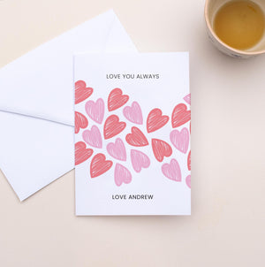 Greeting card with heart pattern and envelope on a beige surface