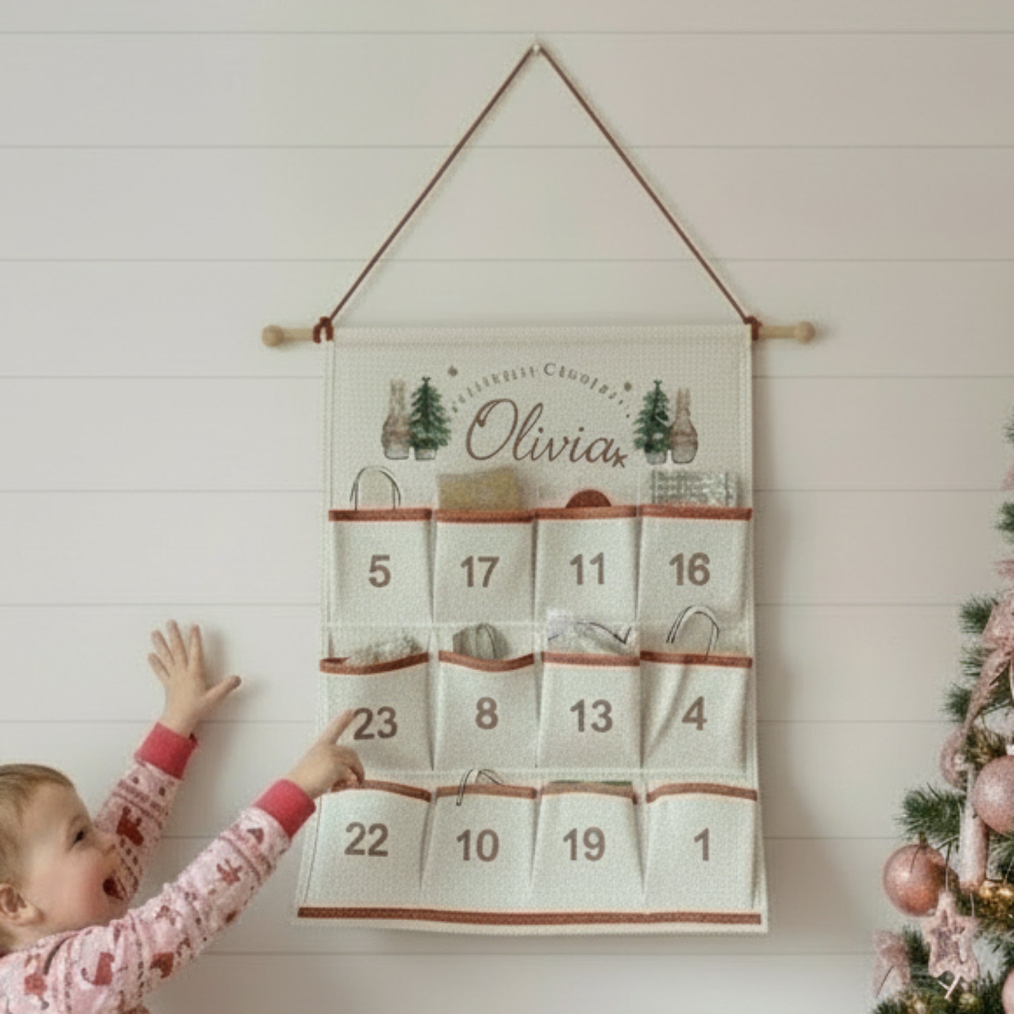 Child reaching towards a Christmas-themed advent calendar hanging on a wall.