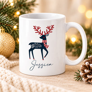 Angled white personalised reindeer Christmas mug with festive pine decorations