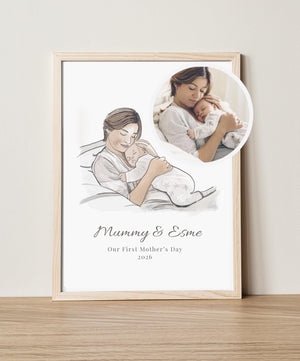 Framed artwork of a mother and child with a inset photo of a woman holding a baby, on a light wooden surface.