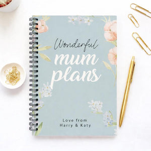 Notebook with 'Wonderful mum plans' text on a white surface with decorative items.