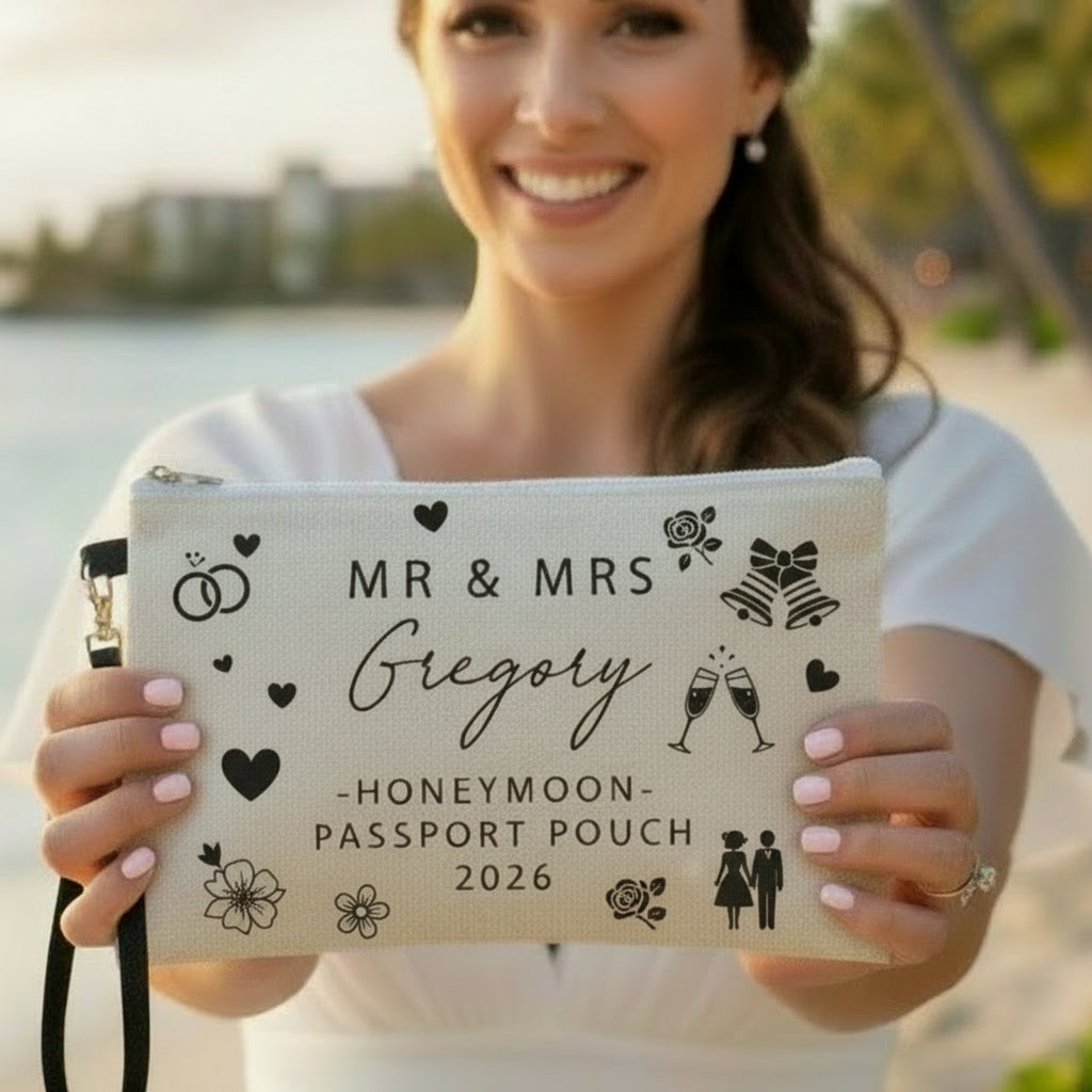 A beige personalized honeymoon passport organizer with black printed text and decorative icons, held in a person's hand.
