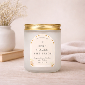 Candle with 'Here Comes the Bride' label on a light surface