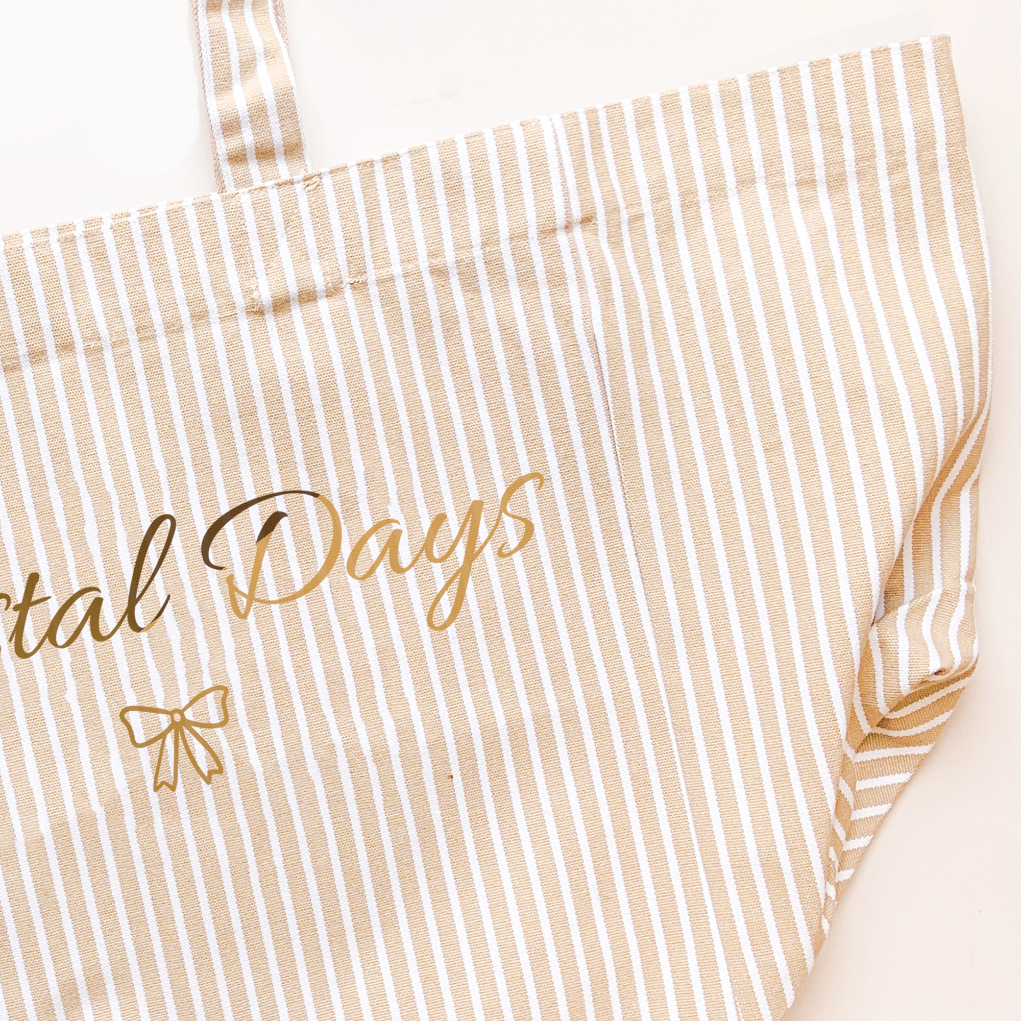 Beige and white striped apron with 'Betal Days' text and bow design.