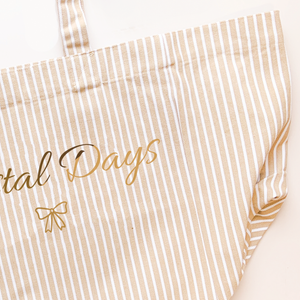 Beige and white striped apron with 'Betal Days' text and bow design.