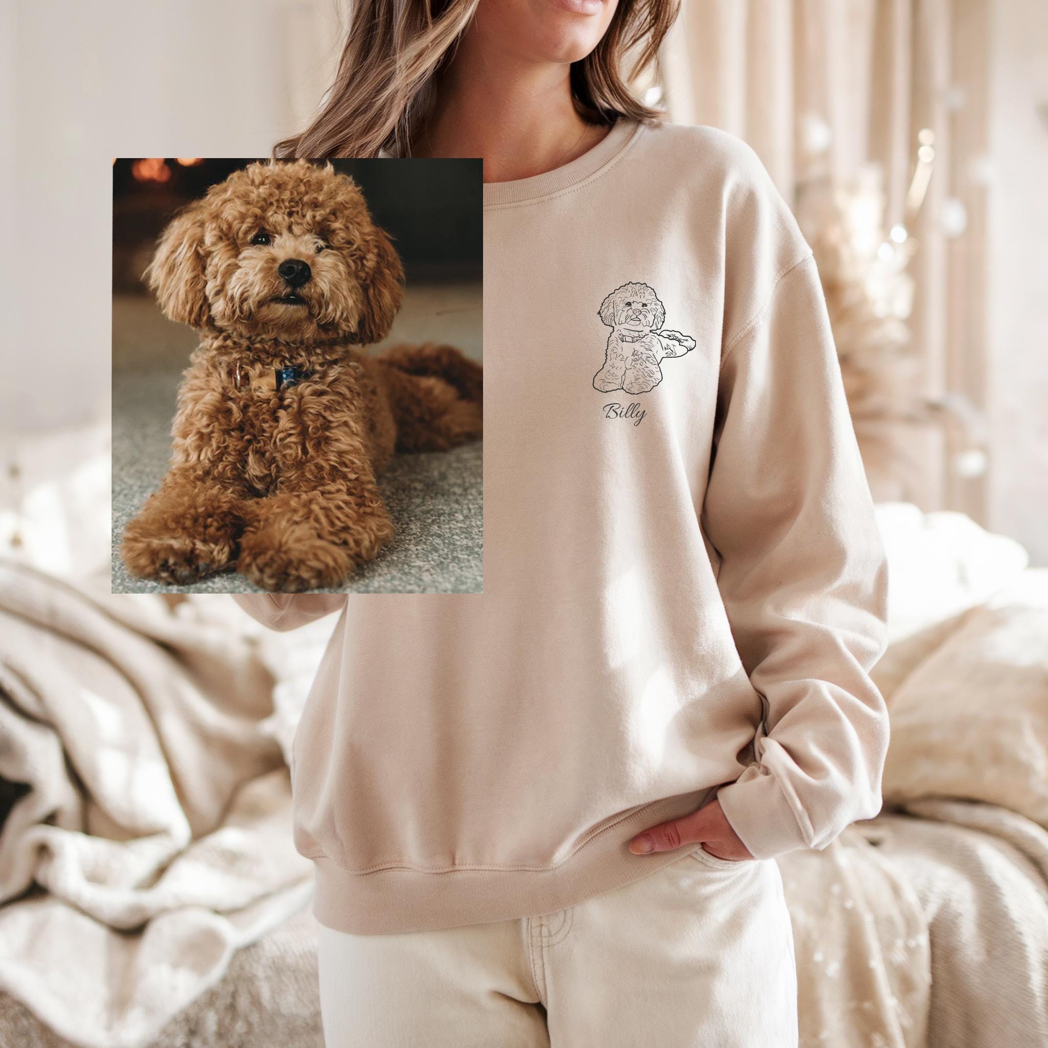 Person wearing a beige sweatshirt with a dog illustration and name, holding a photo of a brown dog.