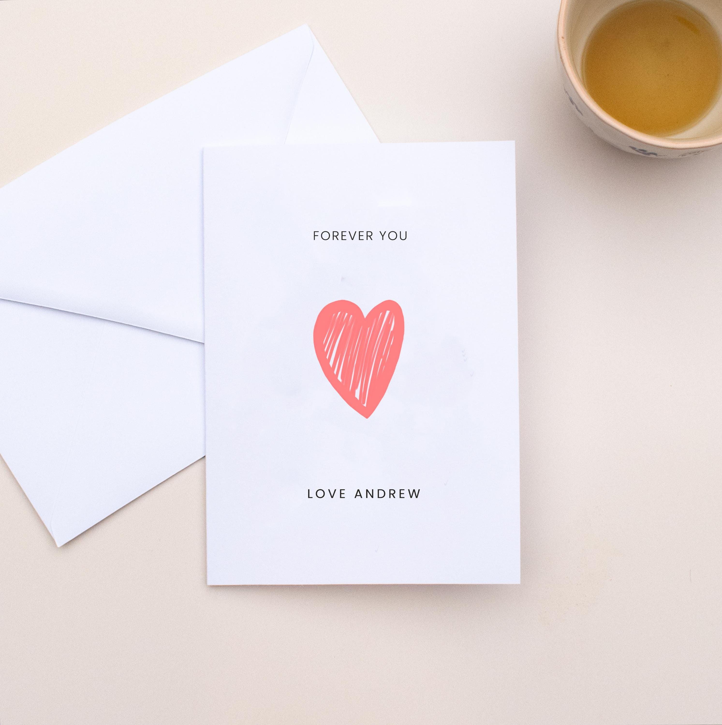 Greeting card with red heart and text 'Forever You' on a beige surface with an envelope.