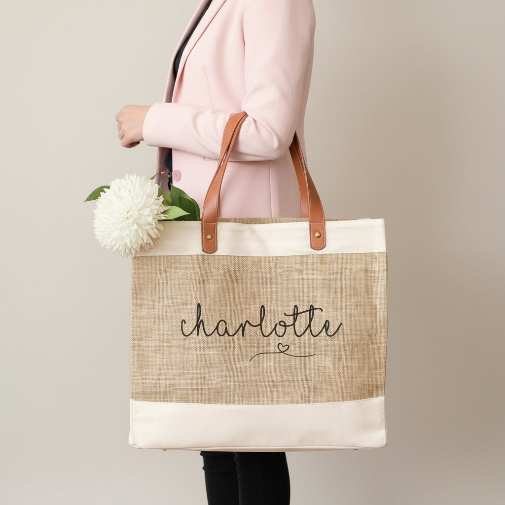 Tote bag with 'Charlotte' printed on it, held by a person with flowers in the background.