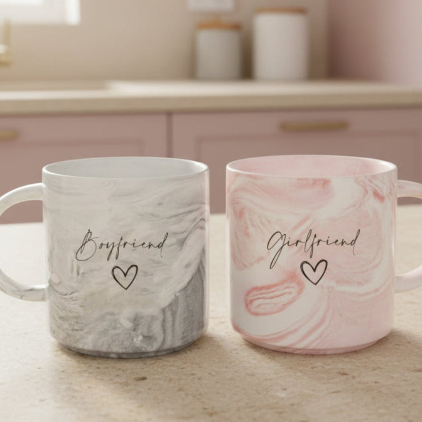 Two mugs labeled 'Boyfriend' and 'Girlfriend' on a wooden surface