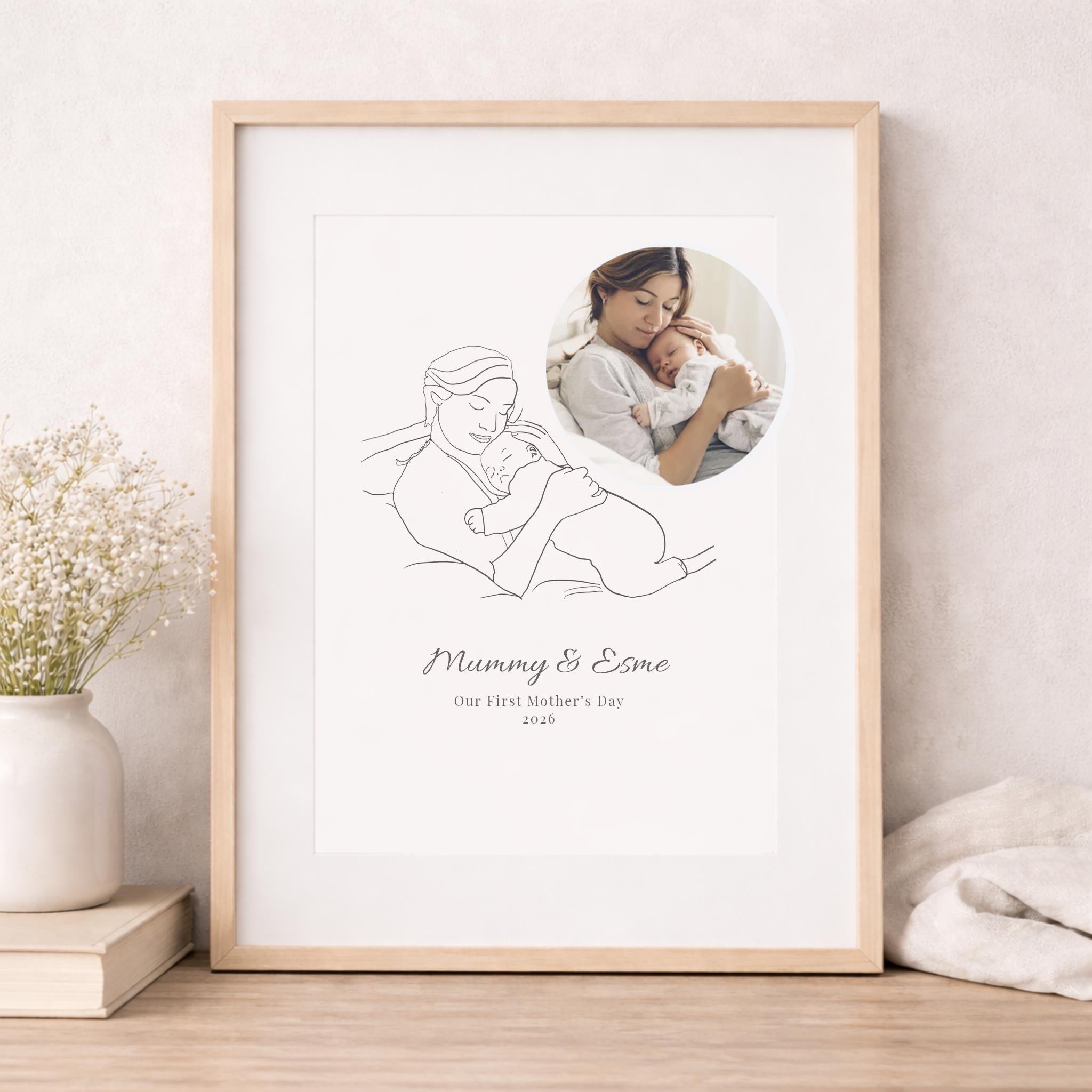 Framed artwork with line drawing of a mother and child and a photo of a woman holding a baby, on a light wooden floor.