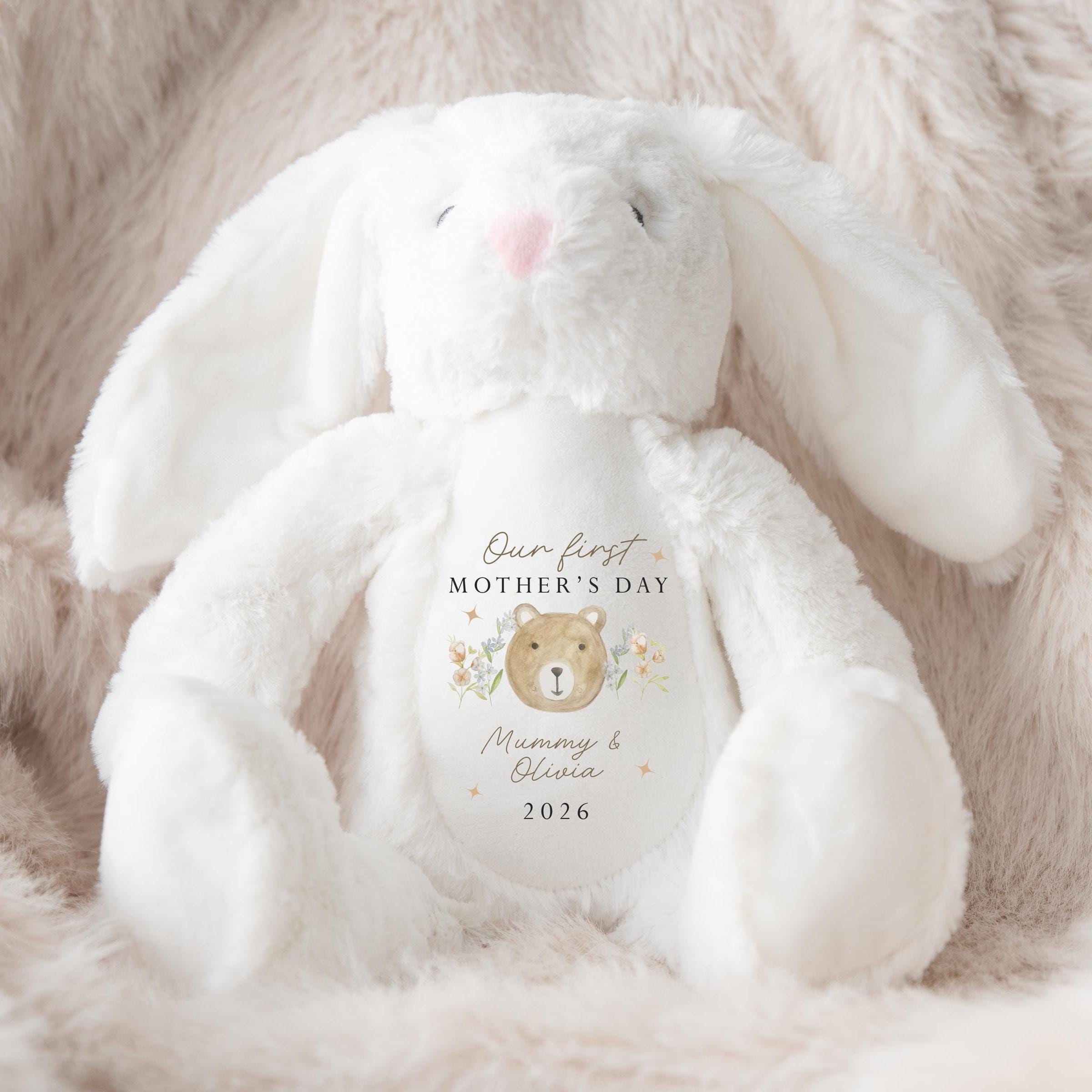 White plush bunny with 'Our first Mother's Day' text on a soft, light brown background