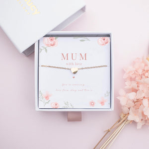 Necklace with a heart pendant on a floral card labeled 'MUM with love' on a pink background.