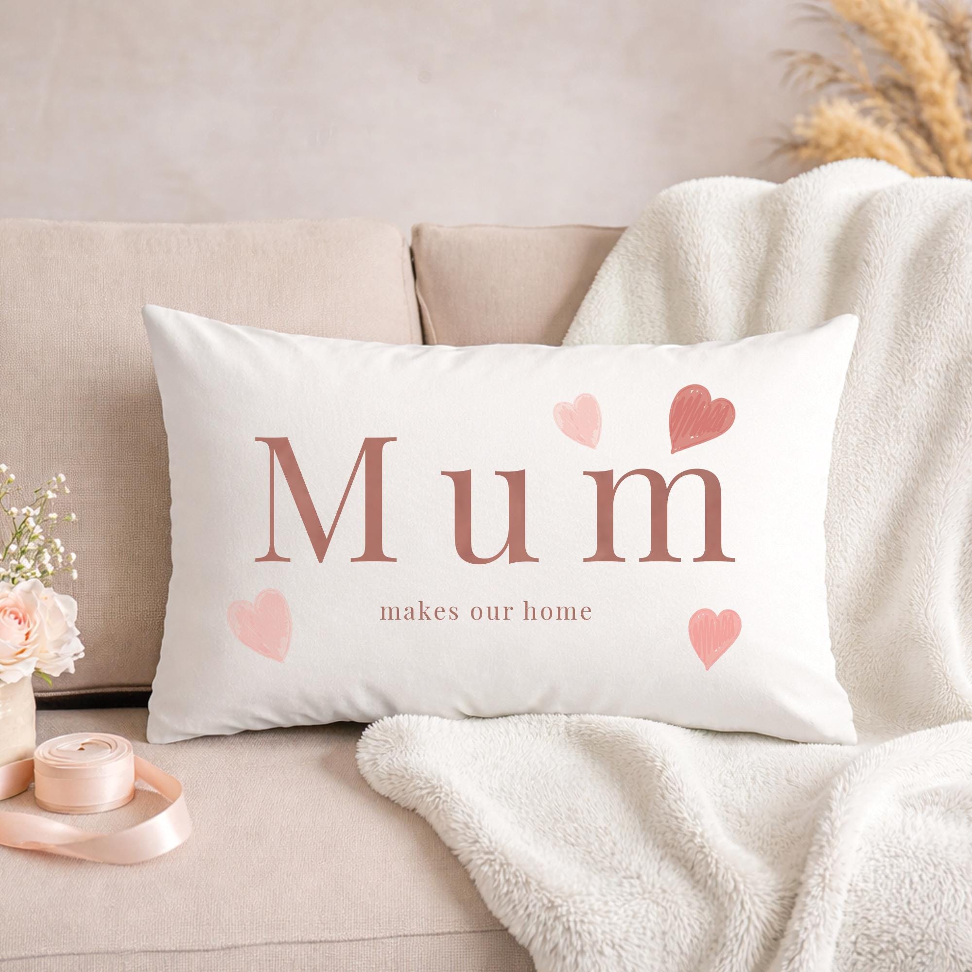 White pillow with 'Mum makes our home' text on a beige couch