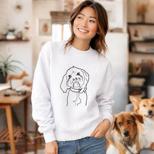Woman wearing a white sweatshirt with a dog illustration, standing in a home setting with two dogs.