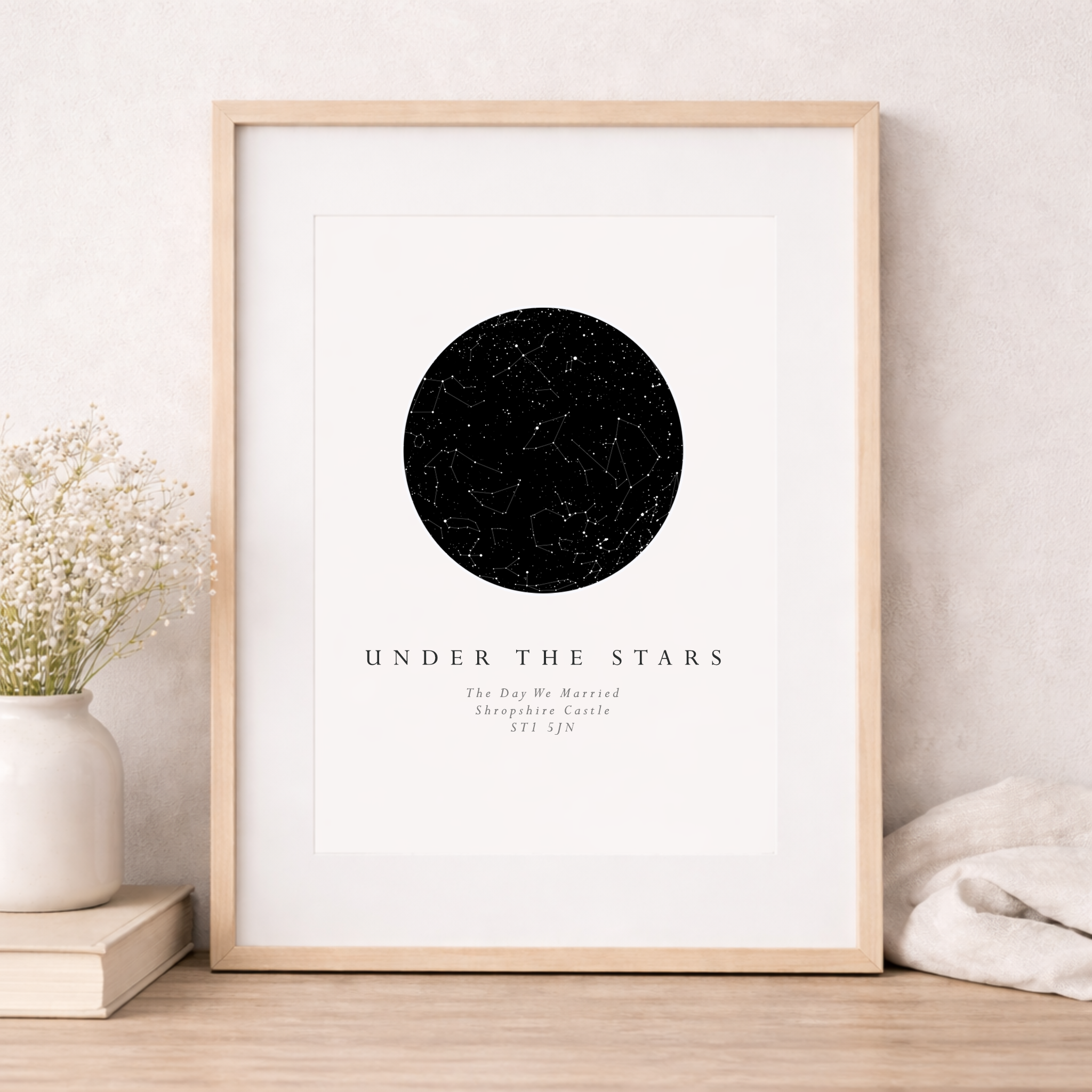 Framed poster with a black circle design on a white background, placed on a wooden surface.